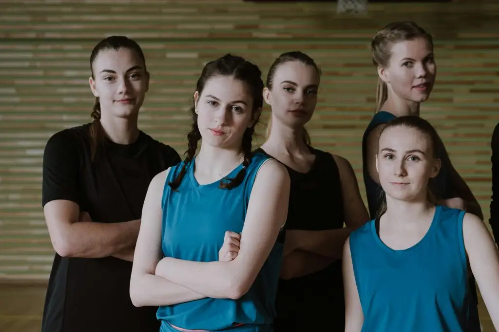 A group of determined young women in sportswear posing confidently in a gym setting.
